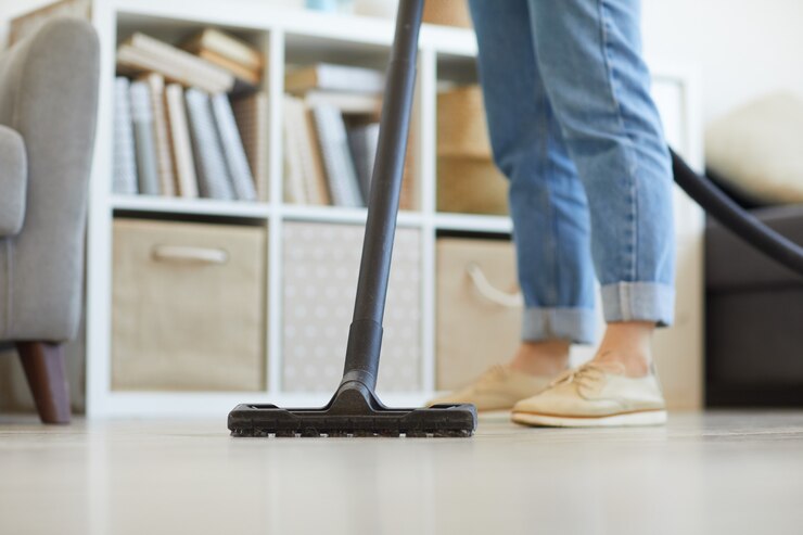 Primer plano de ama de casa con aspiradora y limpieza del piso en casa