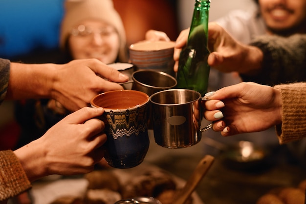 Primer plano de amigos brindando con tazas de bebidas durante la fiesta al aire libre