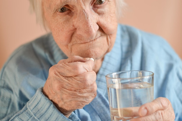 Primer plano de una anciana de 90 años de edad canosa que bebe agua de un vaso Soledad estrés nietos desaparecidos