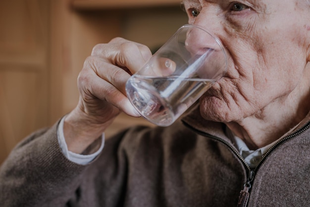 Primer plano de un anciano bebiendo agua