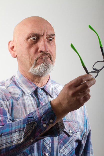 Primer plano de un anciano enojado con gafas contra un fondo blanco