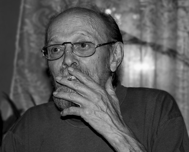 Foto primer plano de un anciano fumando un cigarrillo en casa