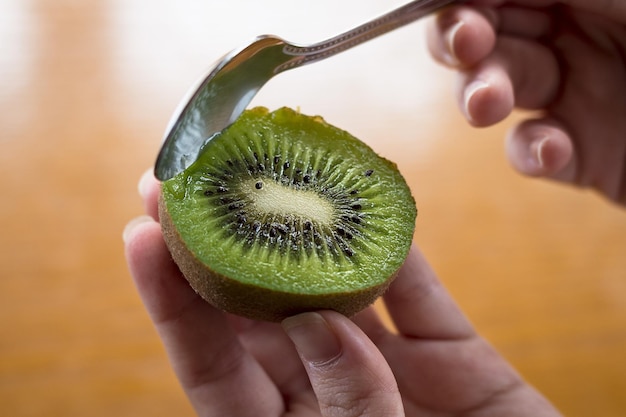 Primer plano de ángulo alto de una persona comiendo kiwi con una cuchara