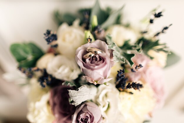 Primer plano de anillos de boda en el fondo de rosas