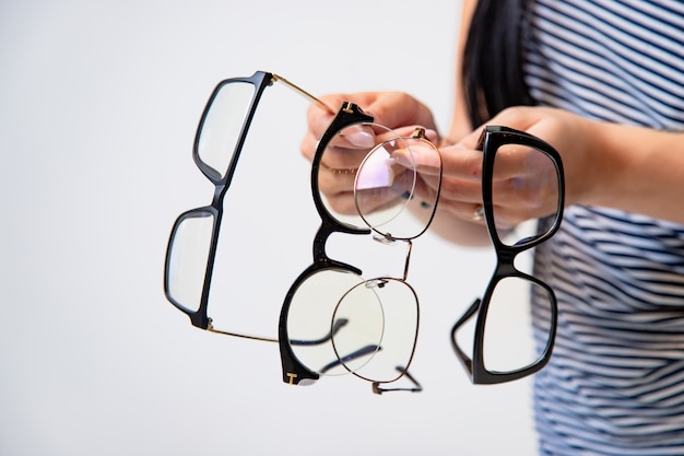 Foto primer plano de anteojos. espectáculos en manos de mujer. muchos vasos. vista frontal. acercarse.