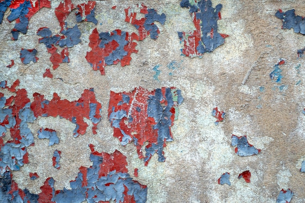 Primer plano antiguo muro de hormigón coloreado. Pared desgastada con pintura azul y roja desconchada. textura agrietada, fondo abstracto.