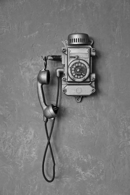 Primer plano de un antiguo teléfono con cable vintage en blanco y negro para la comunicación en una pared gris Teléfono antiguo del pasado para fondos de diseño