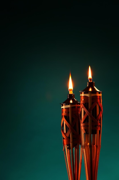 Primer plano de las antorchas tiki iluminadas contra un fondo verde