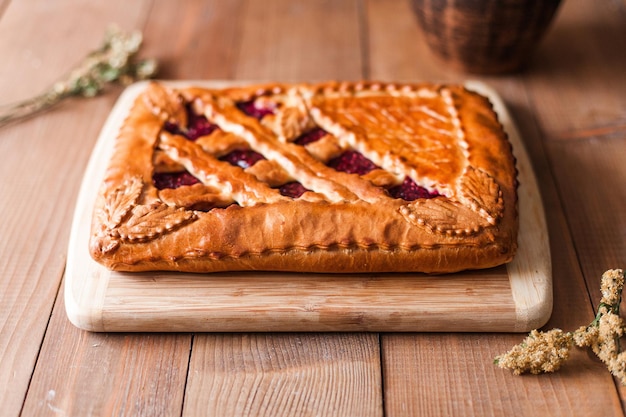 Primer plano de un apetitoso pastel de bayas dulces relleno típico ruso en una tabla de cortar de madera