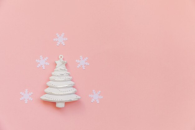 Foto primer plano del árbol de navidad con copos de nieve en fondo rosa