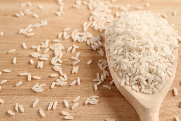 Primer plano de arroz en una cuchara de madera sobre una superficie de madera