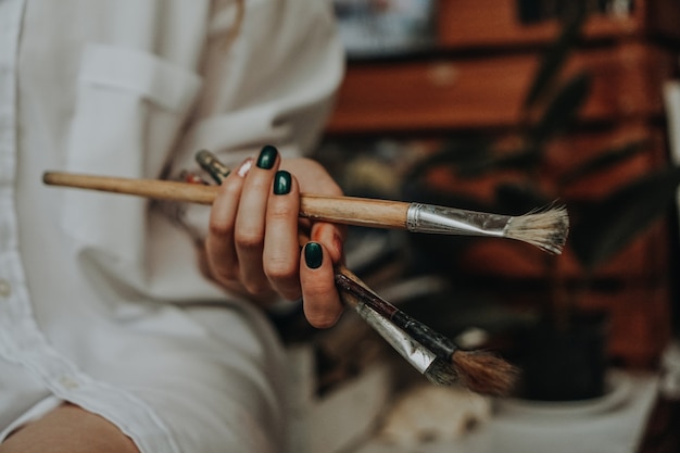 Primer plano de una artista femenina mano sujetando el pincel en el taller de arte