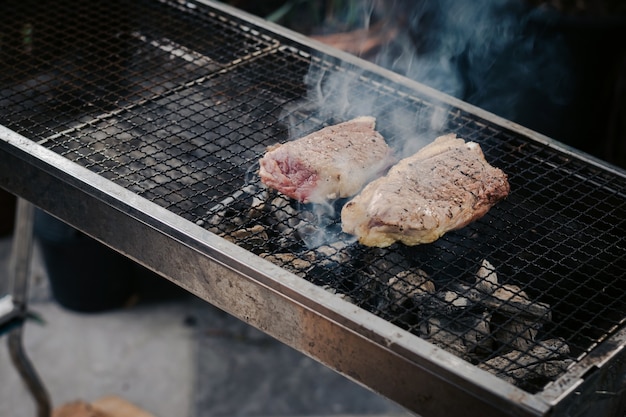 Primer plano Ase la carne en la parrilla de carbón para cocinar bistecs.