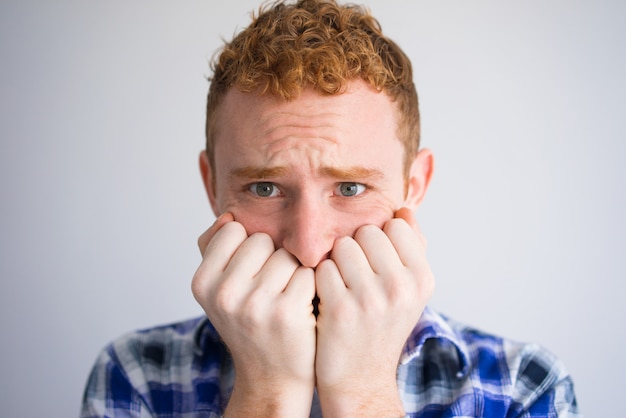 Primer plano, de, asustado, estudiante masculino, morderse las uñas