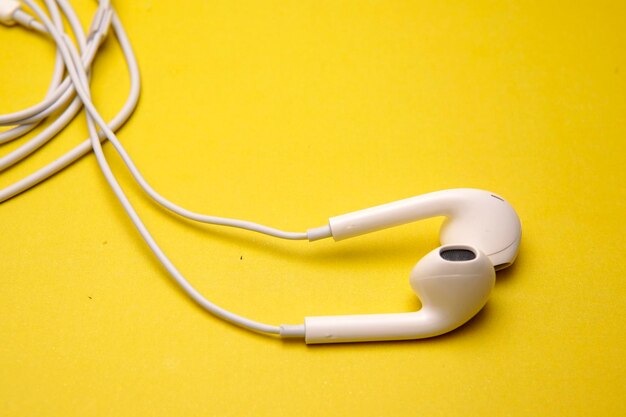 Foto primer plano de auriculares blancos sobre un fondo amarillo