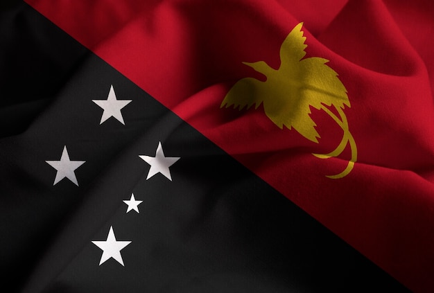 Primer plano de la bandera de Papua Nueva Guinea con volantes, bandera de Papúa Nueva Guinea soplando en el viento