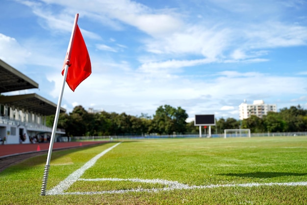 Primer plano de la bandera roja en la esquina de un campo de fútbol con un cielo azul brillante