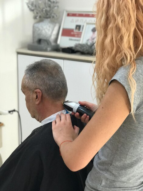 Foto primer plano de un barbero cortando el cabello de un anciano