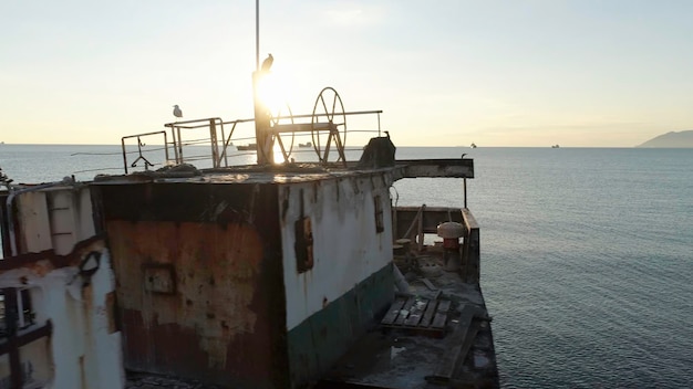 Primer plano de un barco viejo y roto encallado cerca de la costa contra el hermoso cielo al atardecer.