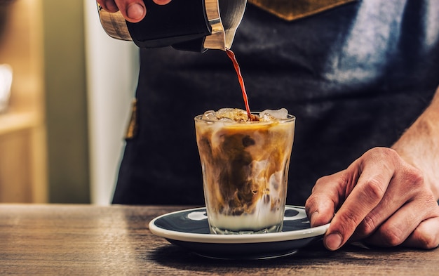 Primer plano de un barista haciendo café con hielo fresco en la barra de bar.