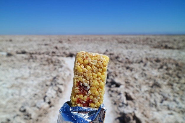 Primer plano de una barra de proteína con un paisaje árido borroso en el fondo