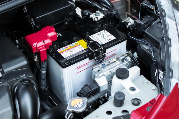 Primer plano de la batería del automóvil en el compartimento del motor Concepto de piezas de automóviles