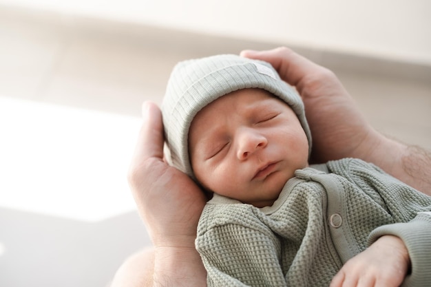 Primer plano de un bebé recién nacido lindo brunet peludo caucásico durmiendoUn niño de dos semanas en manos masculinasHombre irreconocible padre sosteniendo niñoCarelovefelicidad concepto