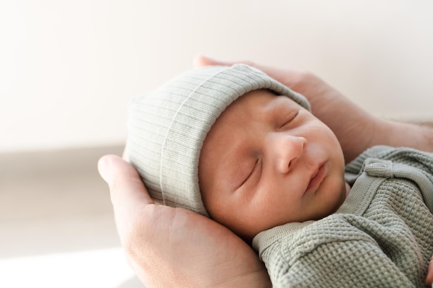 Primer plano de un bebé recién nacido lindo brunet peludo caucásico durmiendoUn niño de dos semanas en manos masculinasHombre irreconocible padre sosteniendo niñoCarelovefelicidad concepto