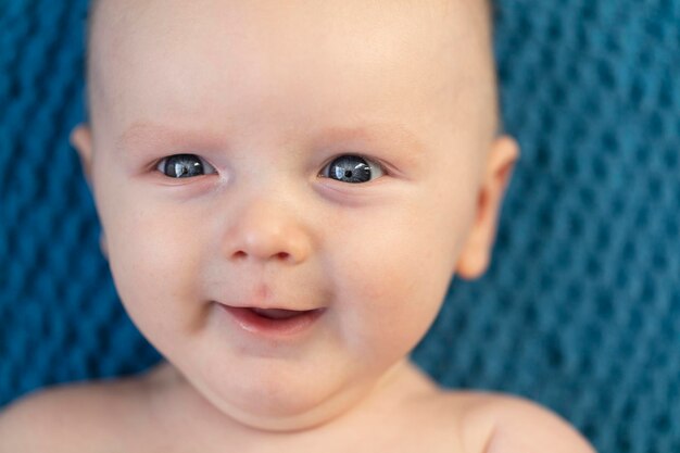 Primer plano de un bebé sonriente feliz contra un fondo de manta azul