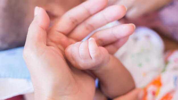 Foto primer plano del bebé sosteniendo la mano de la madre