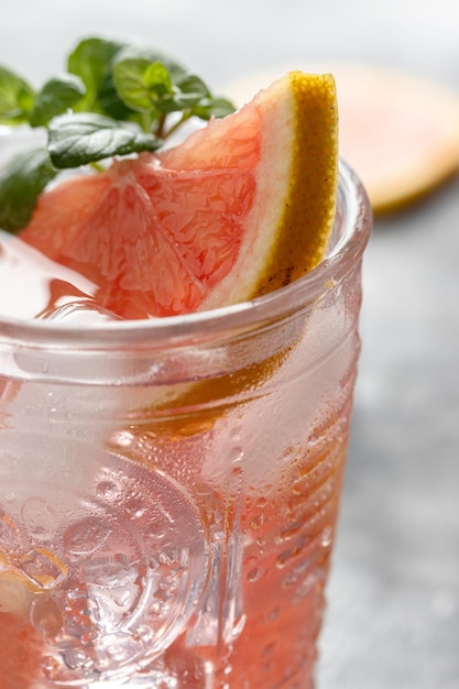 Primer plano de una bebida refrescante de pomelo y menta en un vaso con hielo