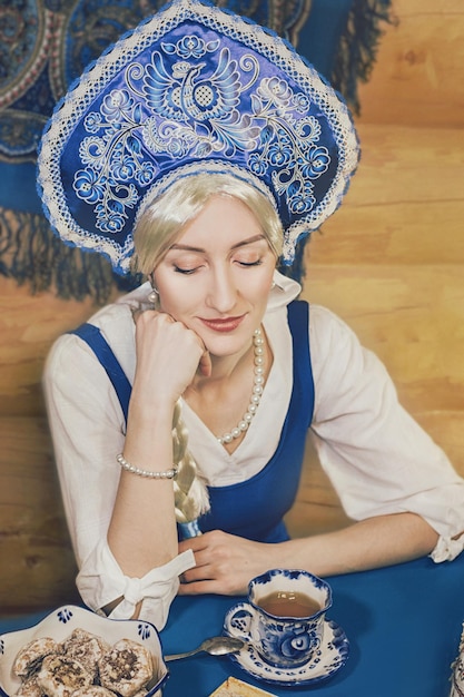 Primer plano de la belleza rusa es beber té con galletas y otra comida deliciosa.