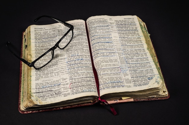 Primer plano de la Biblia y gafas contra un fondo negro
