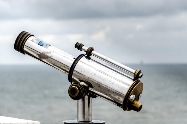 Primer plano de binoculares accionados por monedas en el mar contra el cielo
