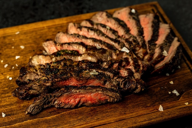 Primer plano de bistec ribeye deshuesado en rodajas servido en una tabla de madera en un restaurante