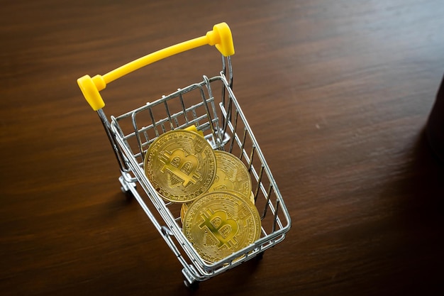 Primer plano de bitcoins dorados o monedas o símbolos de criptomonedas en el carrito de la compra en la mesa Concepto de moneda futura