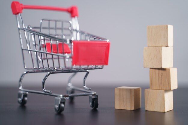 Primer plano de bloques de madera vacíos con carrito de compras en la mesa aislada en gris.