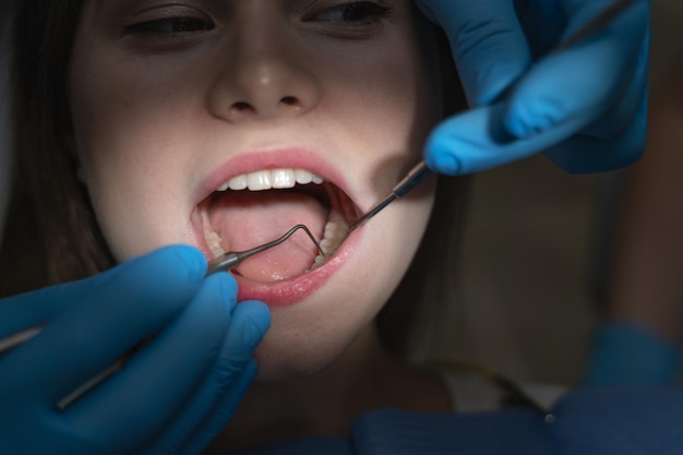 Primer plano de una boca femenina abierta en luz brillante en un consultorio oscuro del dentista. Concepto de tratamiento dental