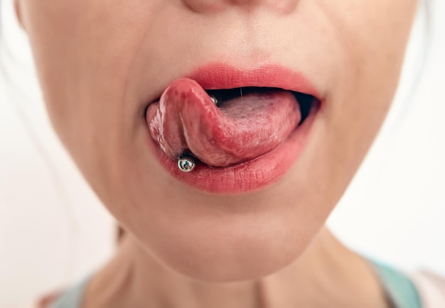 Primer plano de la boca de una mujer con la lengua fuera Piercing en la lengua de una mujer