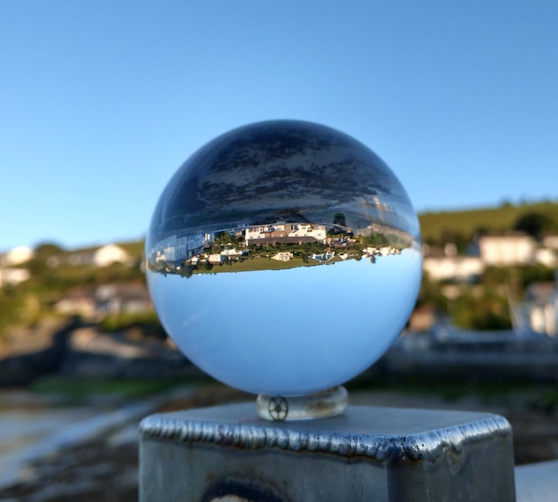 Foto primer plano de una bola de cristal contra el cielo azul y los edificios en el fondo