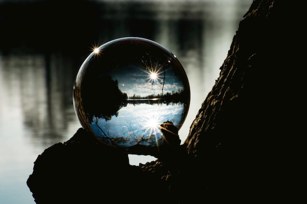 Primer plano de la bola de cristal contra el lago al atardecer