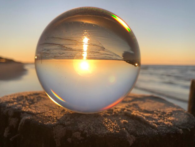 Foto primer plano de la bola de cristal en la playa durante la puesta de sol