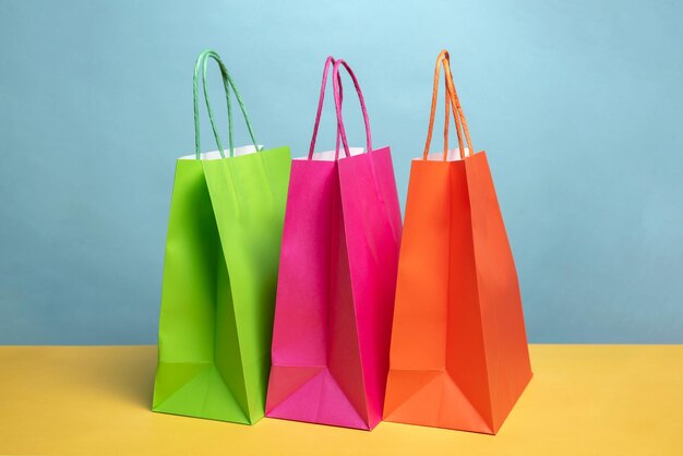 Primer plano de bolsas de compras de varios colores en la mesa contra un fondo azul