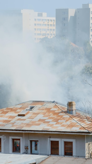 Primer plano de los bomberos en el camión de la plataforma que ayudan con el incendio del edificio en llamas. Bomberos con equipo y agua trabajando para extinguir llamas en el techo de la casa en el paisaje de la ciudad.