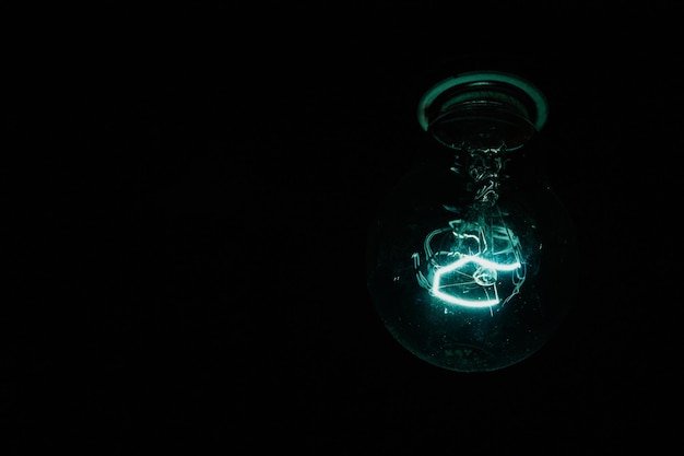 Primer plano de una bombilla iluminada contra un fondo negro