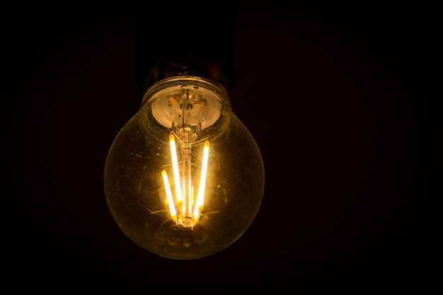 Foto primer plano de una bombilla iluminada contra un fondo negro