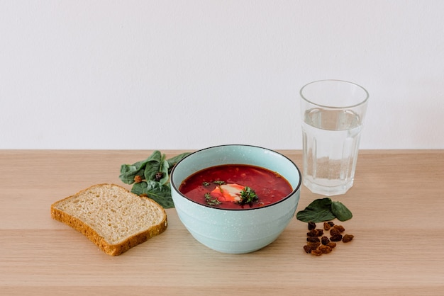 Primer plano de borscht y pan con un vaso de agua