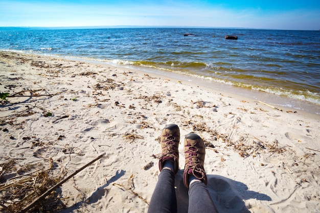 Primer plano de botas de senderismo. niña turista descansando junto al mar