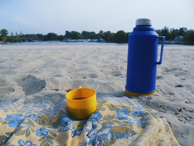 Foto primer plano de una botella de agua en la arena de la playa contra el cielo