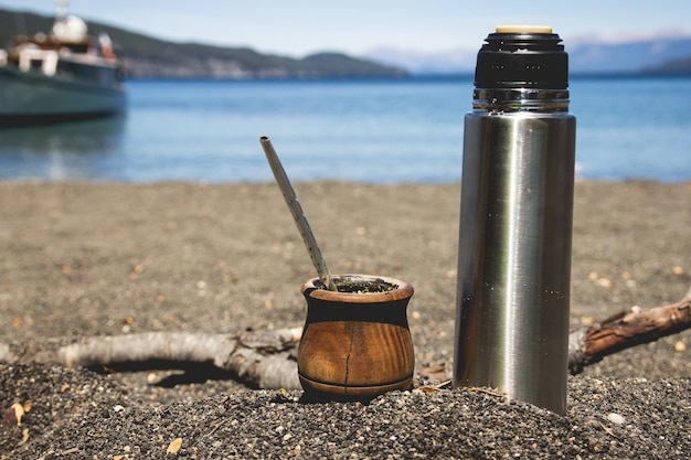 Foto primer plano de una botella de agua con un cuenco en la arena en la playa